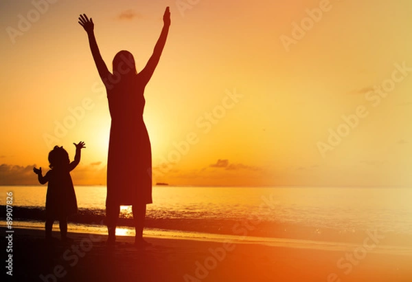Obraz silhouette of mother and little daughter hands up at beach