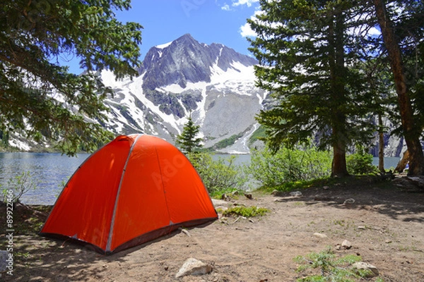 Fototapeta Camping tent in the mountains with lake and snow capped peaks