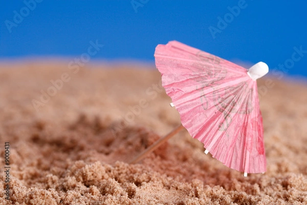 Fototapeta red parasol on beach sand with blue sky background, shallow DOF