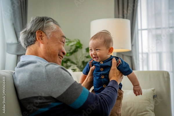 Obraz An older man is holding a baby in his arms. Concept of warmth and happiness between the two