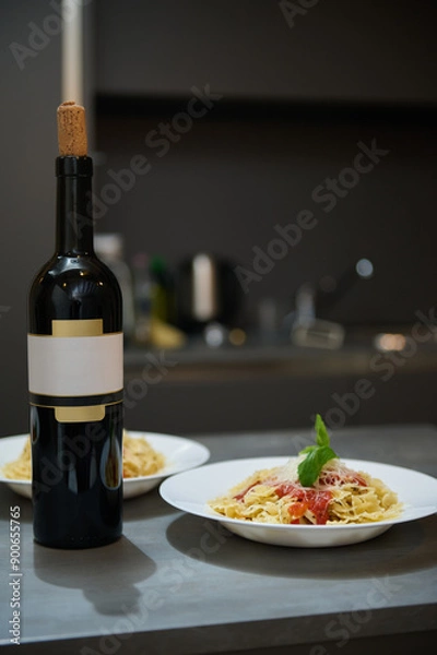 Fototapeta Elegant dinner setup with bottle of wine and pasta plates in a modern kitchen