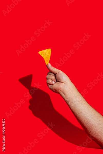 Obraz Hand with tasty tortilla chips or nachos with fresh homemade guacamole and tomato dip sauce on red background