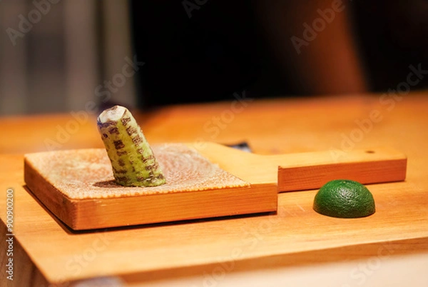 Fototapeta close up view of fresh wasabi on top of wooden culinary board and green lime at Japanese restaurant