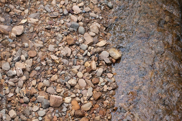 Fototapeta river stone, texture of mixed size of pebbles by the river shore