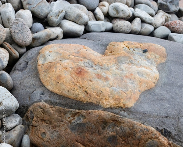 Fototapeta heart shape rock surrounded by small cobbled stones.