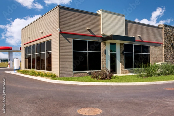 Obraz Modern building with a large glass facade and a beige brick base.  The architectural design suggests that this building could be an office or institutional structure.