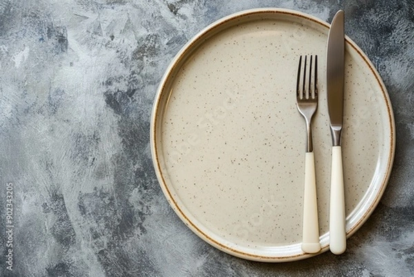Fototapeta Empty plate, knife and fork on concrete background. Top view.