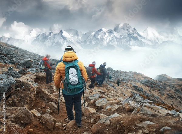 Fototapeta Group of backpackers walking down mountain trail with Himalayan mountains in background during trek in Langtang National Park, Nepal.