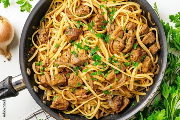 Fototapeta A pan filled with linguine pasta, cooked chicken liver, sautéed onions, and garnished with fresh parsley
