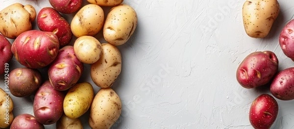 Fototapeta Top view of fresh organic potatoes on a white backdrop with copy space image