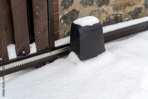 Fototapeta Sliding gate on a fence in the snow in winter.