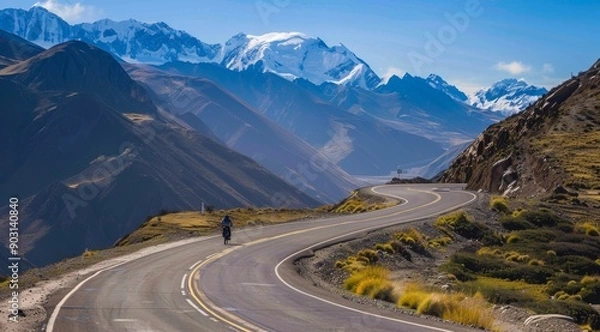 Fototapeta Winding mountain road ina Valley, California with snow-capped mountains and golden rocks on the sides. mountain range with snow capped mountains in the distance and a cloudy sky.