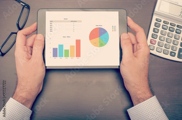 Fototapeta Businessman checking statistics on tablet device