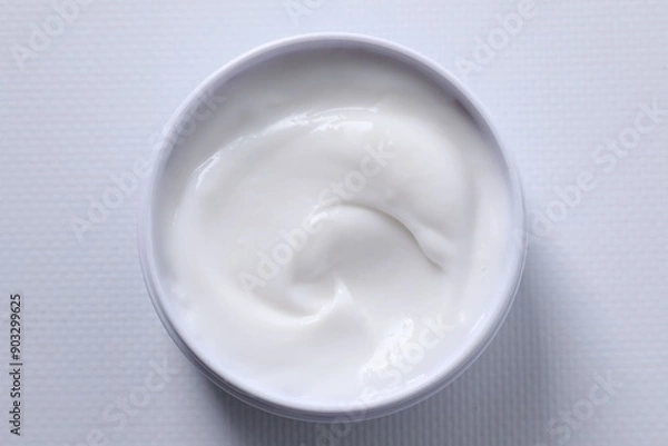 Fototapeta Face cream in jar on white textured table, top view