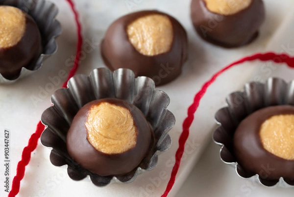 Obraz Smooth and Creamy Buckeye Chocolate and Peanut Butter Candies / Chocolates on White Background with red ribbon