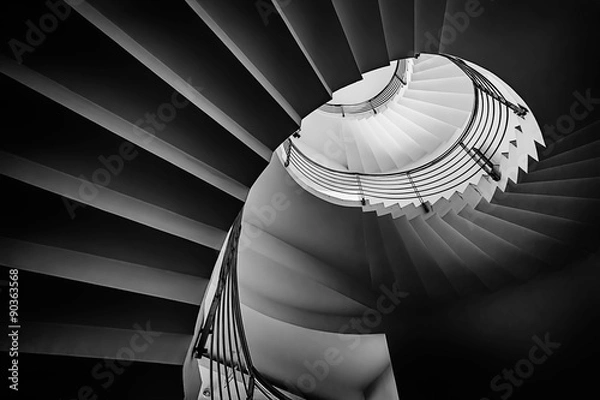 Fototapeta Black and white photograph of spiraling staircase shot from low angle.