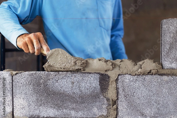 Fototapeta Construction workers are building cement walls with brick blocks.