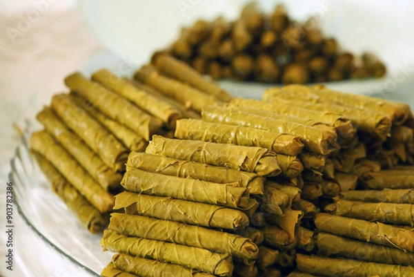 Fototapeta Homemade stuffed vine leaves are arranged in a row on the table,