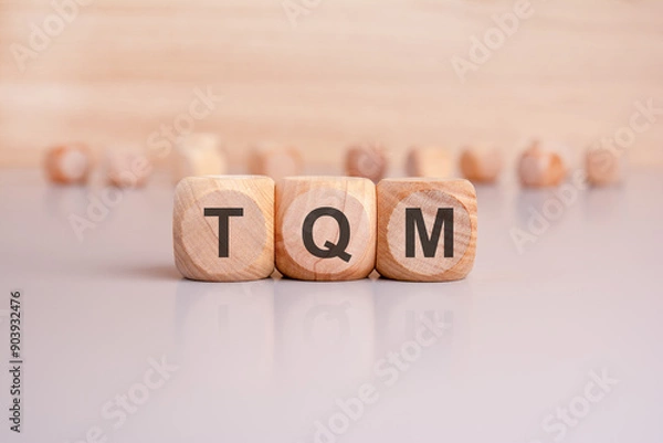 Fototapeta Total Quality Management is creatively displayed on wooden blocks, showcasing its efficiency boost