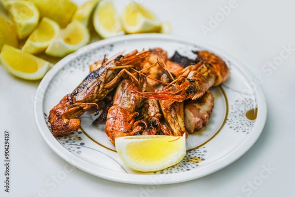 Obraz A plate with grilled shrimp and lemon slices on a white background