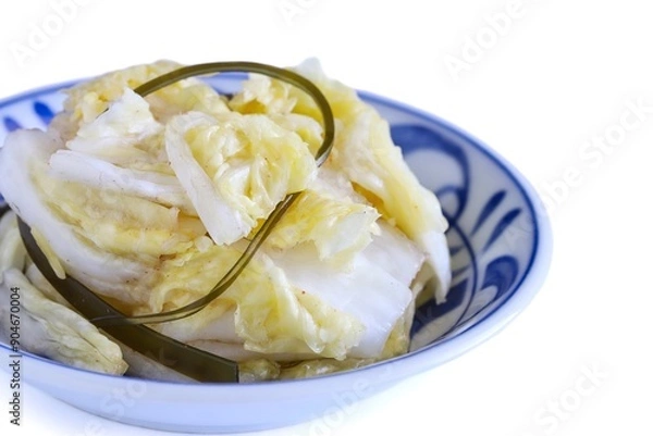 Fototapeta A close up shot of Japanese style pickled Chinese cabbage on a porcelain plate on white background.