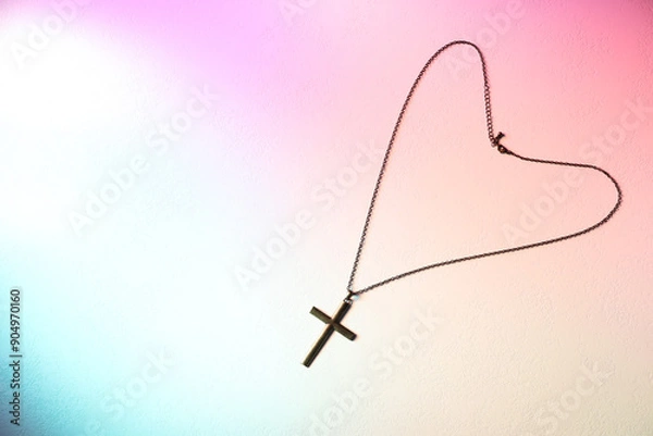 Fototapeta Cross with chain on textured table in color lights, top view and space for text. Religion of Christianity