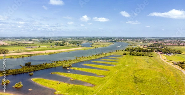 Fototapeta Aerial photo of the flood plains along the Lek River with a train bridge and the city of Culemborg on the horizon.
