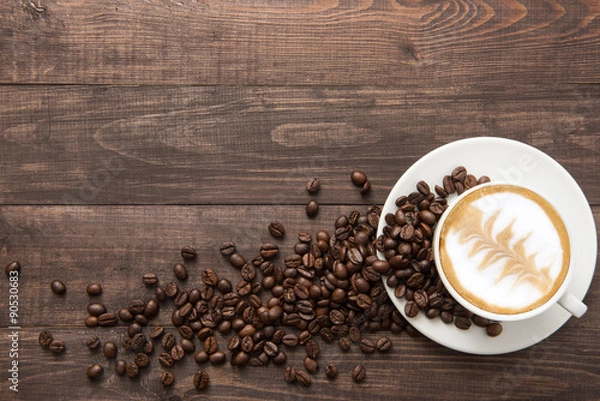 Obraz Coffee cup and coffee beans on wooden background. Top view.