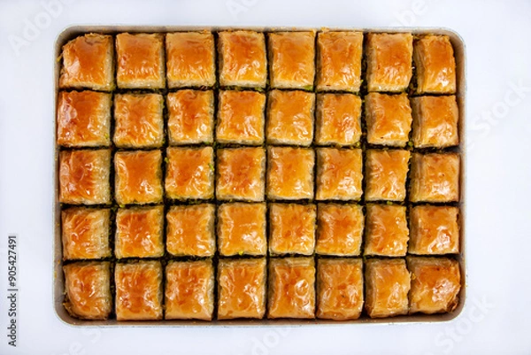 Fototapeta Top view of baked pistachio or walnut baklava on a tray isolated on white background.