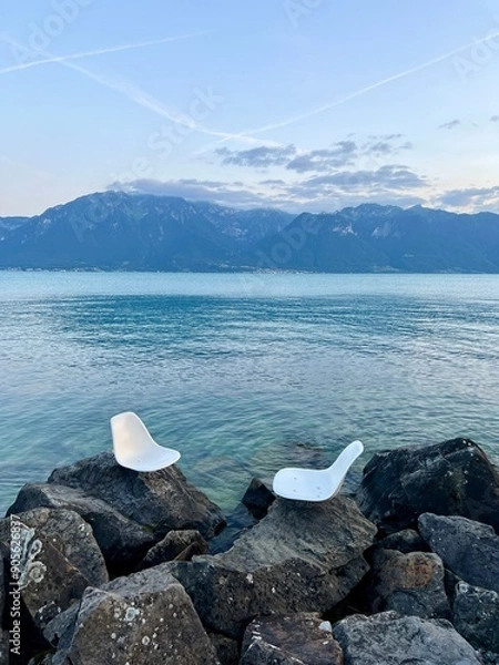 Obraz Vevey, Switzerland, view of lake Geneva and the Swiss Alps.  Two chairs set on the rocks to look out into the lake and surrounding landscape.