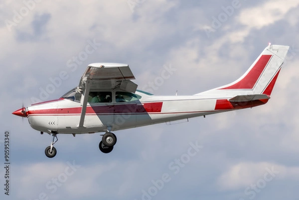 Fototapeta Unmarked and generic high wing general aviation aircraft.  Red stripe on white paint of a piston powered propeller driven airplane on approach to landing