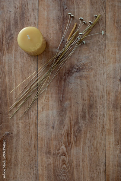 Fototapeta Top down view of a yellow candle and dried field flowers on a oak wood surface with copy space.