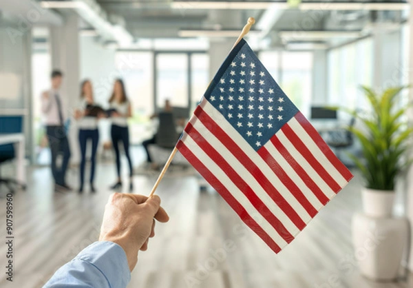 Obraz Close up of an American flag being held in the style of one person in the foreground, blurred people holding US flags and dressed in business casual standing behind him in a blurry background.
