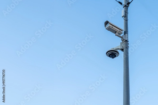 Obraz Security camera and dome camera on a pole with clear sky in the background