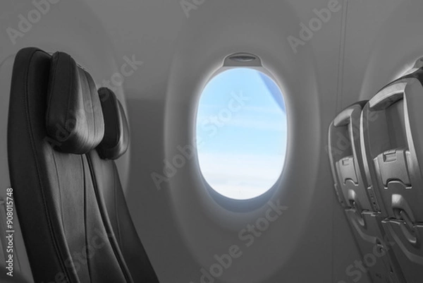Fototapeta Comfortable black seats and window on the plane with a view of blue sky