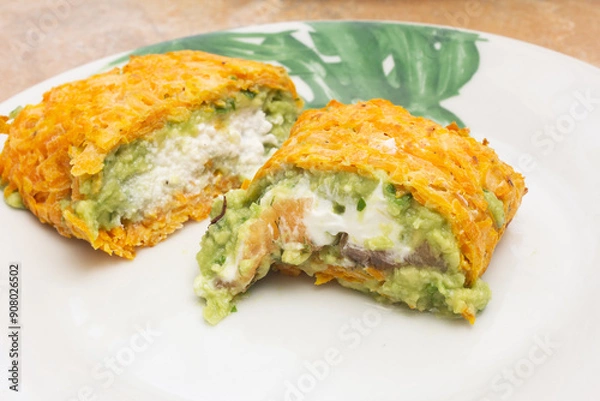 Fototapeta Close-up of two cut pieces, one filled with creamy ricotta cheese and the other with marinated smoked salmon and cream cheese, both wrapped in a baked carrot layer. Healthy food for wellness.