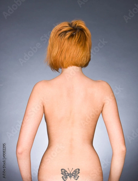 Fototapeta The girl a back  with a tattoo in the form of the butterfly