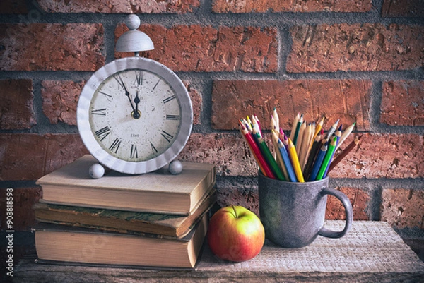 Obraz Back to school - clock, books and school supplies on bricks background