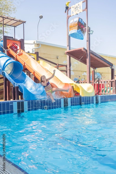 Obraz Chica caucásica de 9 años deslizándose por un tobogán de agua en una piscina