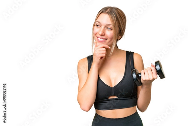 Fototapeta Blonde sport woman making weightlifting over isolated chroma key background thinking an idea and looking side