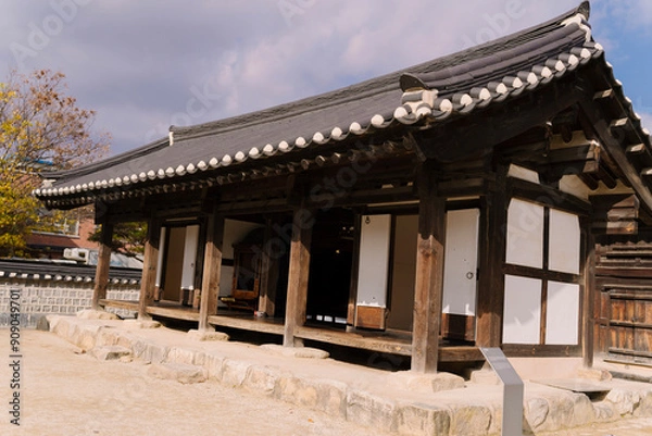 Fototapeta the traditional Korean architecture at Gyeonggijeon Shrine, featuring wooden beams, a tiled roof, and white walls under a clear blue sky.