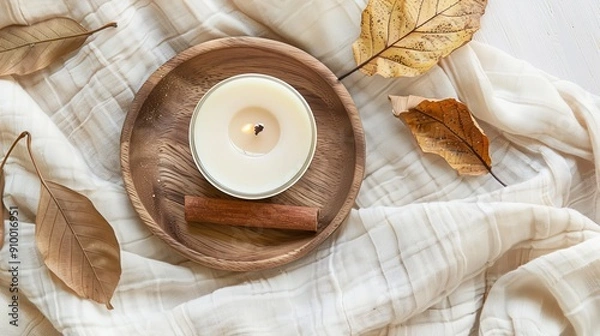 Fototapeta Top view cinnamon scented candle on the wooden round plate and leaves