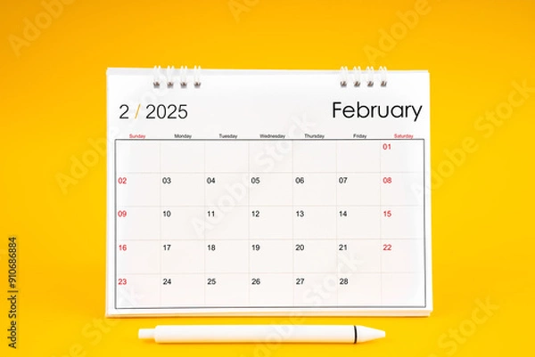 Fototapeta February 2025, Monthly desk calendar for 2025 year and pen on yellow background.