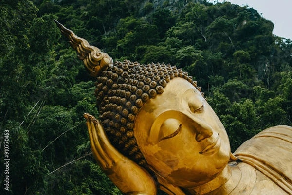 Fototapeta Close up of Reclining Buddha gold statue face with mountain background inThailand.