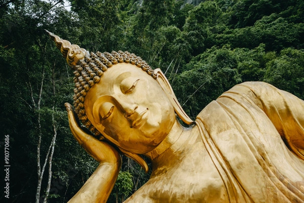 Fototapeta Close up of Reclining Buddha gold statue face with mountain background inThailand.