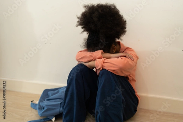 Obraz Unhappy child sitting on the floor in a school, expressing sorrow and isolation, capturing the essence of bullying and emotional distress
