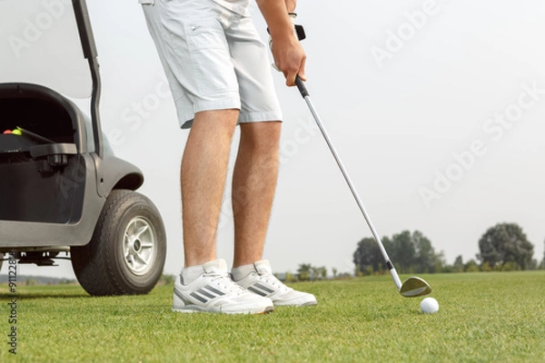 Fototapeta Young golfer getting ready to hit the ball