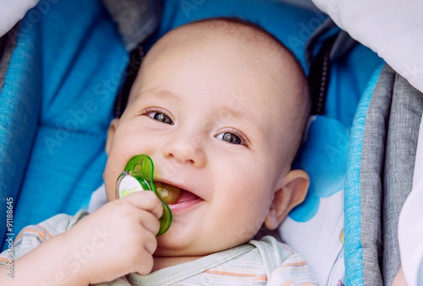 Fototapeta happy baby with pacifier in a stroller