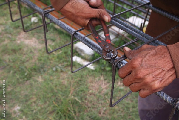 Obraz Construction workers use wire to tie structural steel without wearing gloves