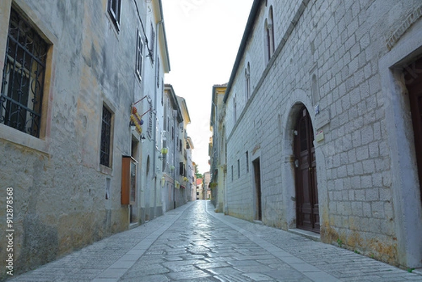 Fototapeta A narrow cobblestone street lies nestled between two historic stone buildings